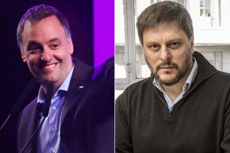 Dois homens aparecem lado a lado, o primeiro tem a pele branca, cabelo castanhos escuros ficando grisalhos, paletó azul escuro e camisa azul clara, ele está sorrindo e acenando e parece estar em um comício; o segundo tem cabelo castanho claro, pele branca e barba, está usando um casaco preto e uma camisa azul clara por baixa, está sentado e com o rosto sério